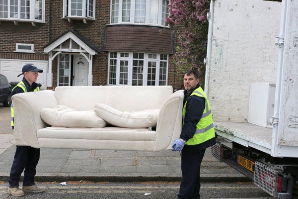 Furniture removal company team lifting couch in Rochester home